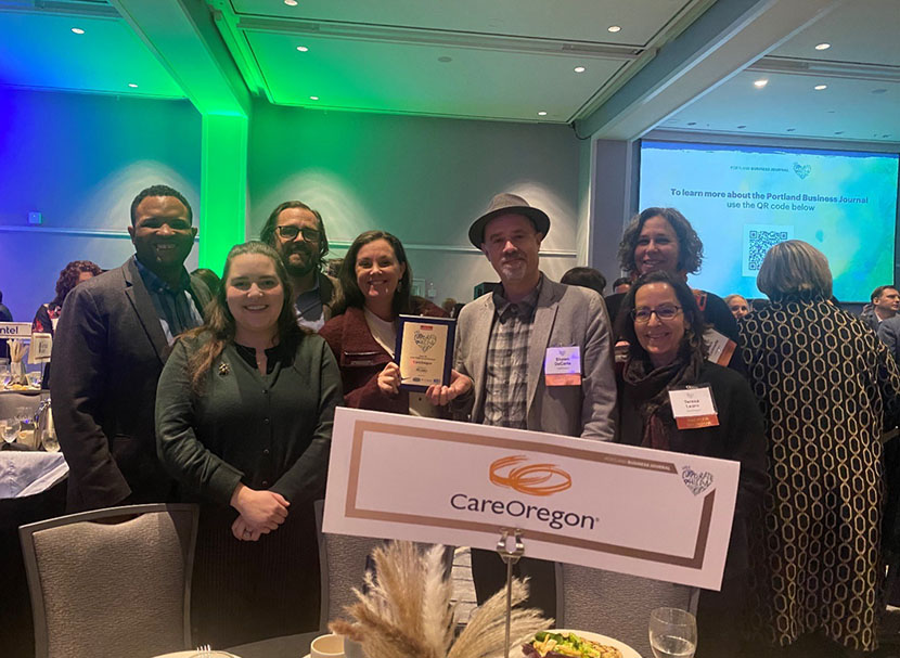 A group of CareOregon employees holding a plaque awarded to the company.