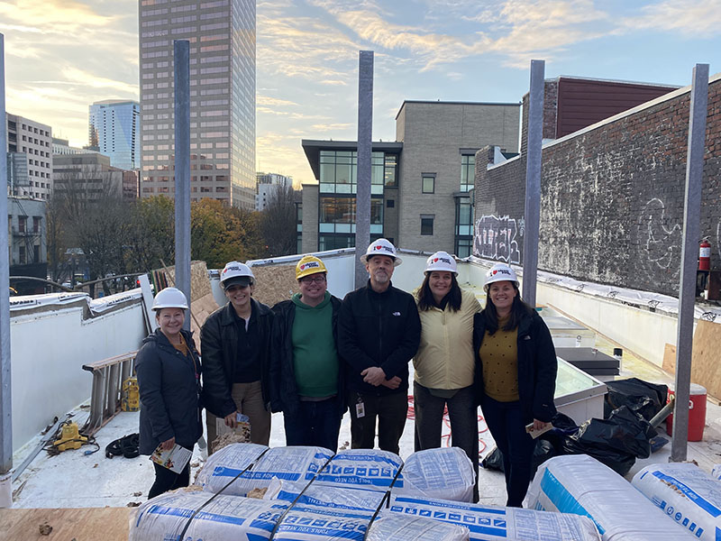 CareOregon employees pose together with hard helmets on building construction site