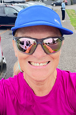 ratina-selfie Close up of a woman's face, smiling, wearing sunglasses, in a blue cap and fuscia shirt