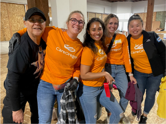 volunteerism-2 Группа женщин в оранжевых рубашках CareOregon стоит в комнате, которая находится на стадии строительства