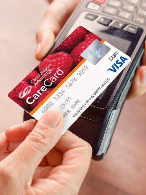 A hand passes the CareOregon Advantage Visa CareCard over a debit card reader.