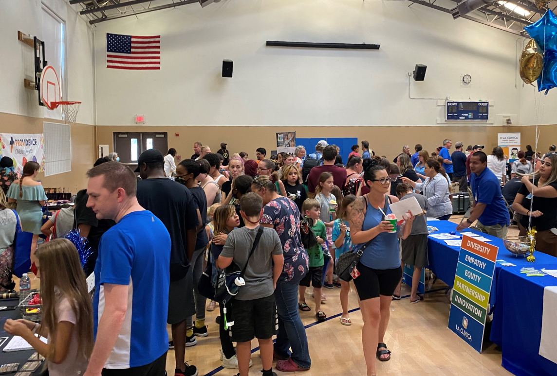 Families and children mill around a health fair in a school gym, stopping at tables staffed by local businesses and services, including CareOregon’s Connect to Care team.