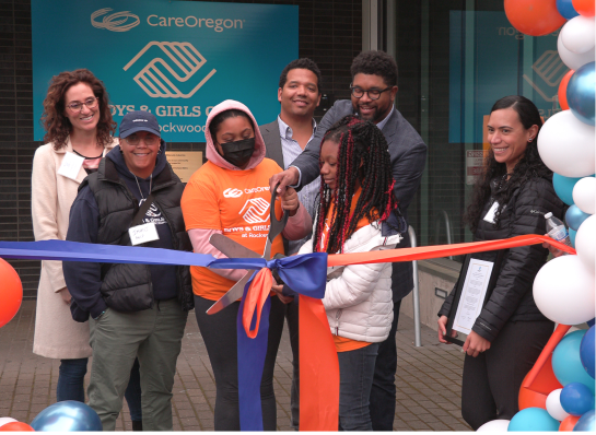 A group of people participating in a ribbon-cutting ceremony outside the CareOregon Boys & Girls Club at Rockwood.  