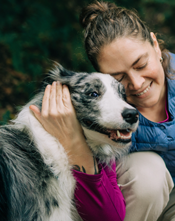 Woman outside with arm wrapped around dog