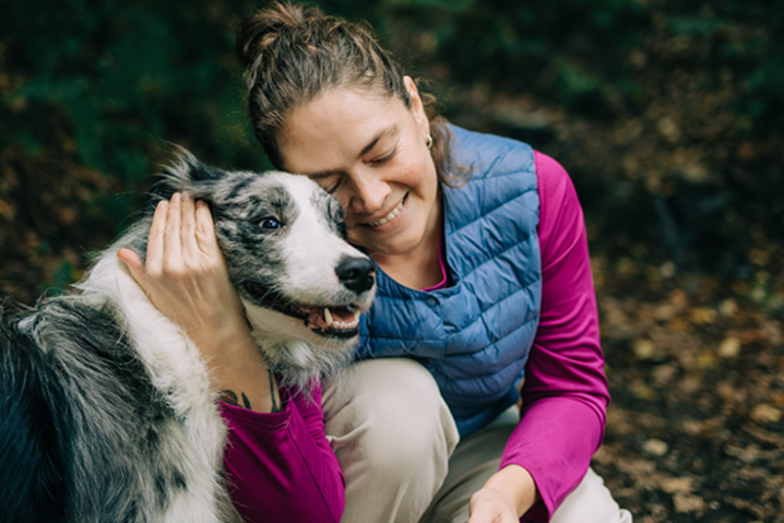 Woman outside with arm wrapped around dog