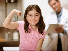 Niña en consultorio médico flexionando el brazo después de recibir su vacuna.