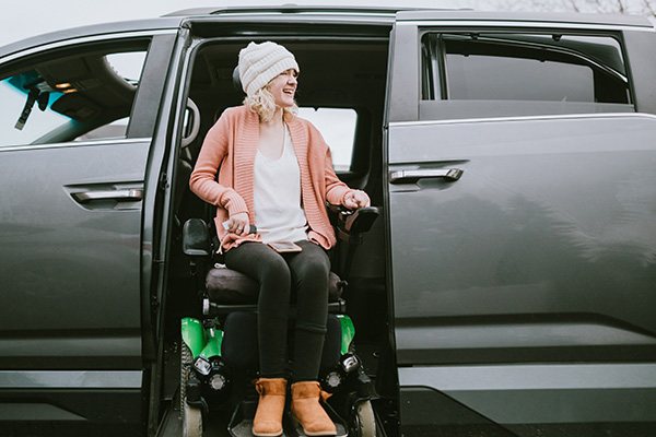 Woman in a wheelchair getting out of a van using a wheelchair lift