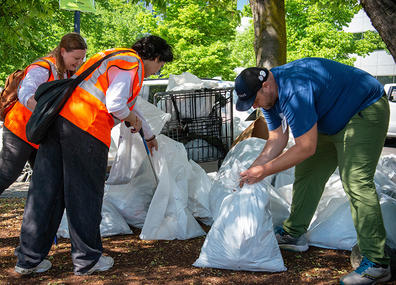 Tres miembros del equipo de CareOregon atan varias bolsas de basura en el evento de limpieza Solve 2023