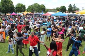 a large, diverse crowd of people gathered in a park for good in the hood festival